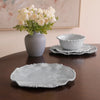 Set of light blue ceramic dishes on a wooden table with a vase of white flowers.