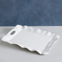 White ceramic tray with wavy edges on a gray surface with a blue background