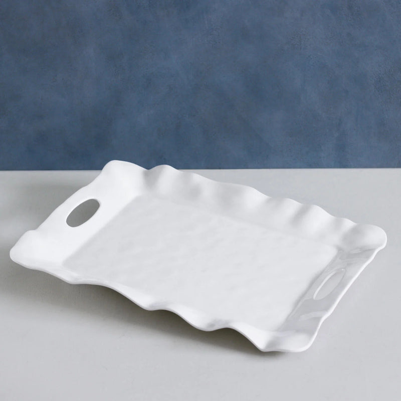 White ceramic tray with wavy edges on a gray surface with a blue background