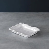 White ceramic dish with decorative edge on a gray surface