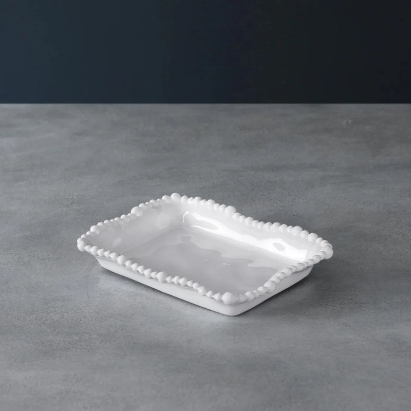 White ceramic dish with decorative edge on a gray surface