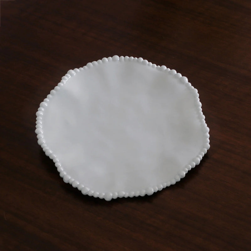 White ceramic plate with decorative edge on a dark wooden surface