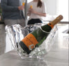 Bottle of champagne in a glass ice bucket with people in the background