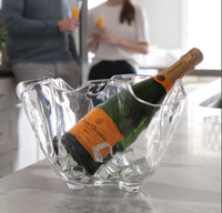 Bottle of champagne in a glass ice bucket with people in the background