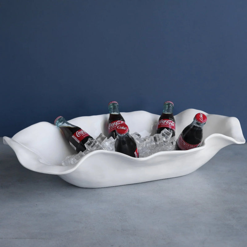 White wavy ice bucket with Coca-Cola bottles on a gray surface and blue background