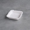 White ceramic dish with decorative edge on a gray concrete surface