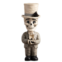 A decorative skeleton figurine styled as a man in a top hat and suit, holding a small box with a ring, photographed against a plain white background.