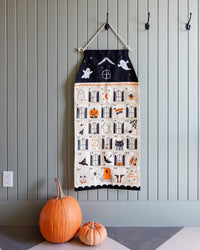 Canvas Halloween advent calendar by My Mind's Eye featuring a whimsical haunted house design with treat pockets and a hanging ribbon for counting down to Halloween.