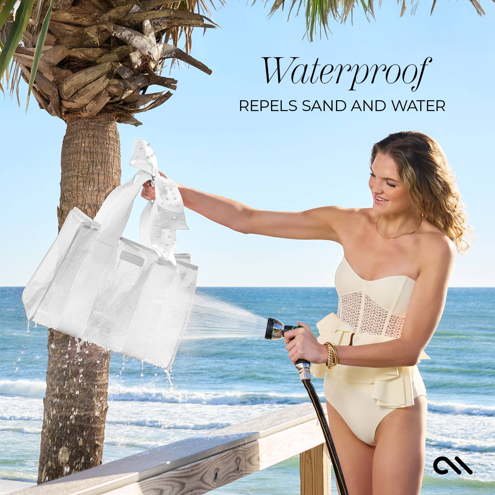 Woman holding a white mesh bag under a shower of water on a beach with palm trees.
