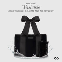 Black tote bag with a bow on a white background, featuring washing instructions.