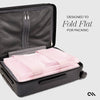 Black suitcase with pink folded fabric inside, labeled 'Designed to Fold Flat for Packing'.