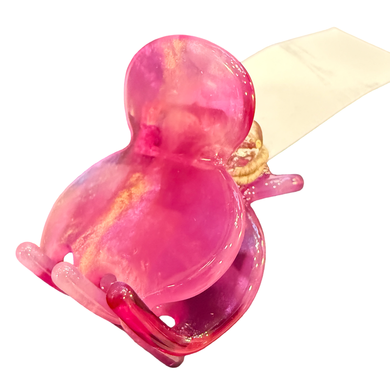A translucent pink glass frog-shaped ring holder with a cream-colored ribbon wrapped around its neck, isolated on a white background.