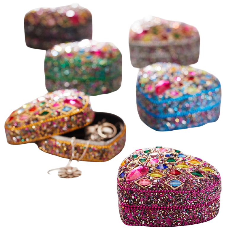 Five heart-shaped beaded jewelry boxes in different colors, decorated with colorful rhinestones and one open box showing rings inside, on a plain white background.