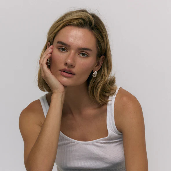 Woman wearing a white tank top against a plain background