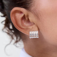 Silver hoop earrings worn by a person with a neutral background