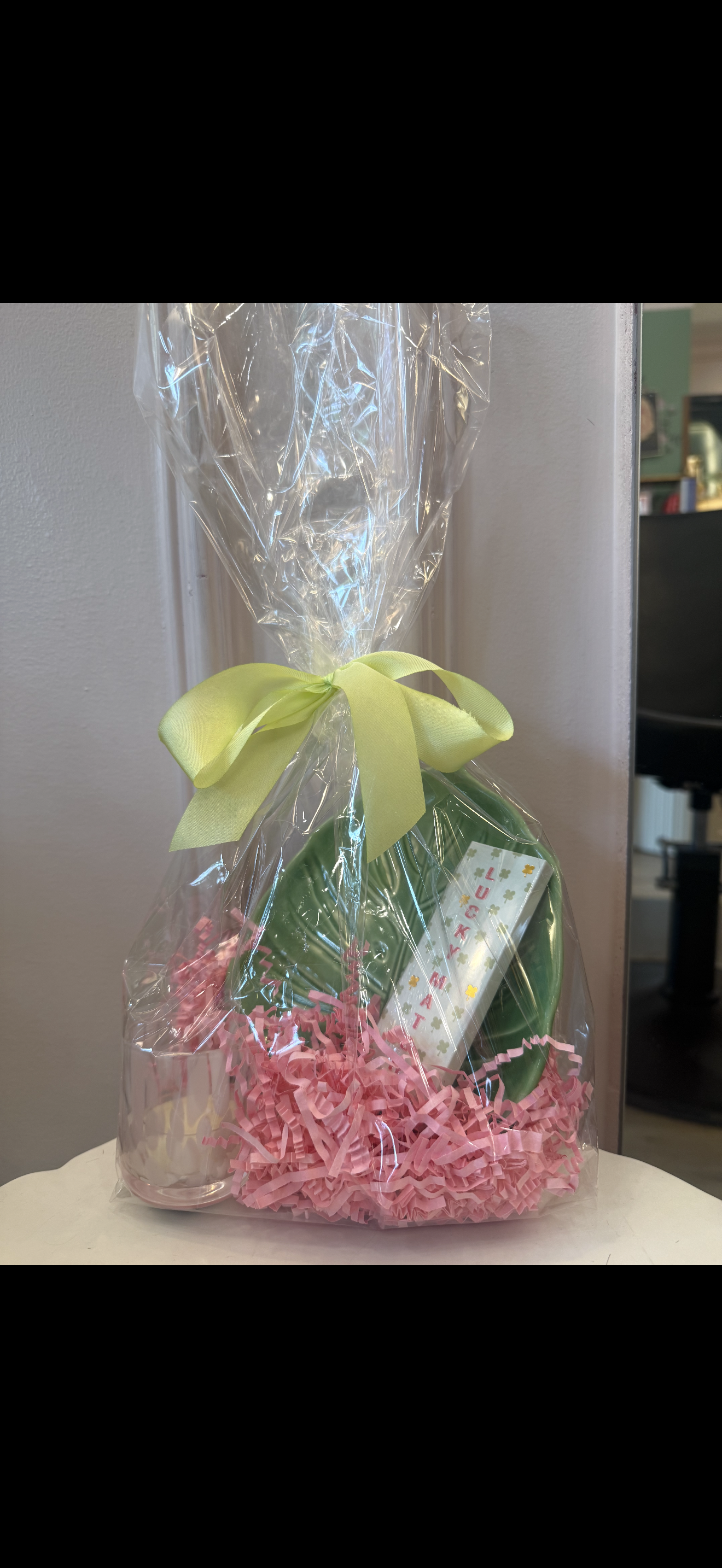 Gift wrapped in clear cellophane with pink tissue paper and a green bow.