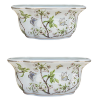 Two ceramic planters with floral and butterfly design on a white background