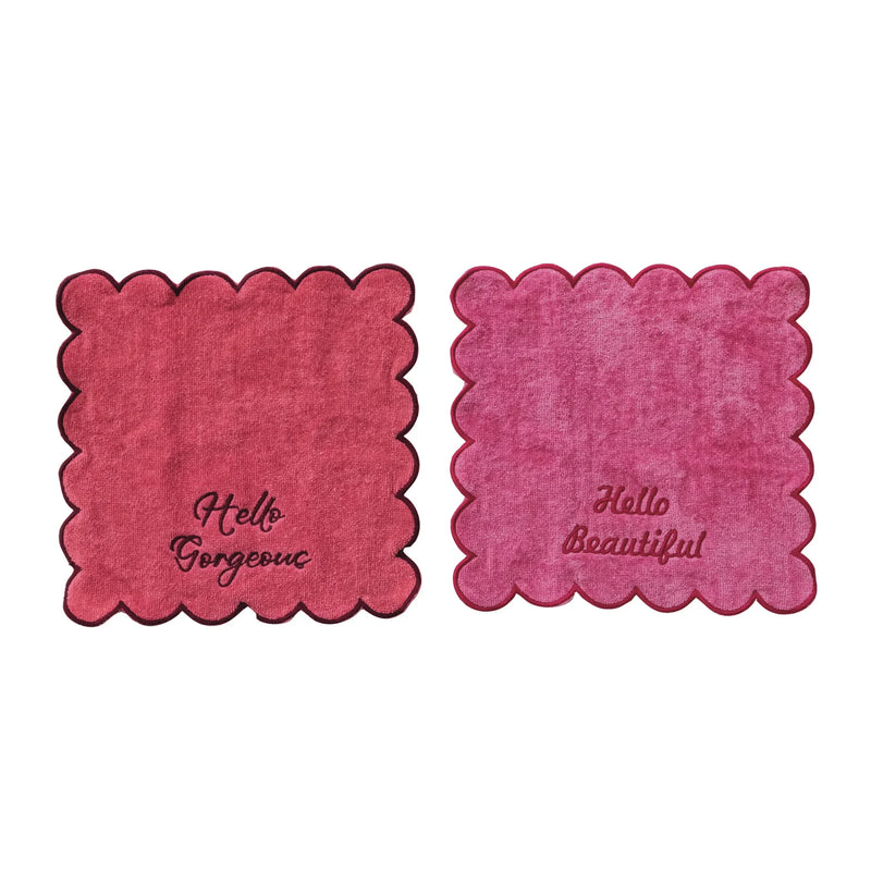 Two pink coasters with scalloped edges and text on a white background