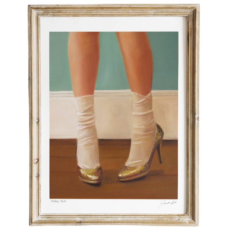 Framed artwork of legs wearing white stockings and gold high heels on a wooden floor.