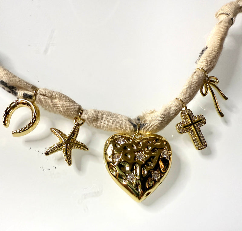 Mandriana, scarf necklace, heart charm necklace, handmade charm jewelry, beachy boho accessory, cross charm necklace, starfish necklace, symbolic jewelry, neutral bandana necklace, one of a kind statement piece, artisanal jewelry, boho chic accessories, charm scarf necklace, textured heart necklace