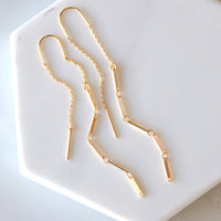 Gold chain earrings on a white hexagonal plate