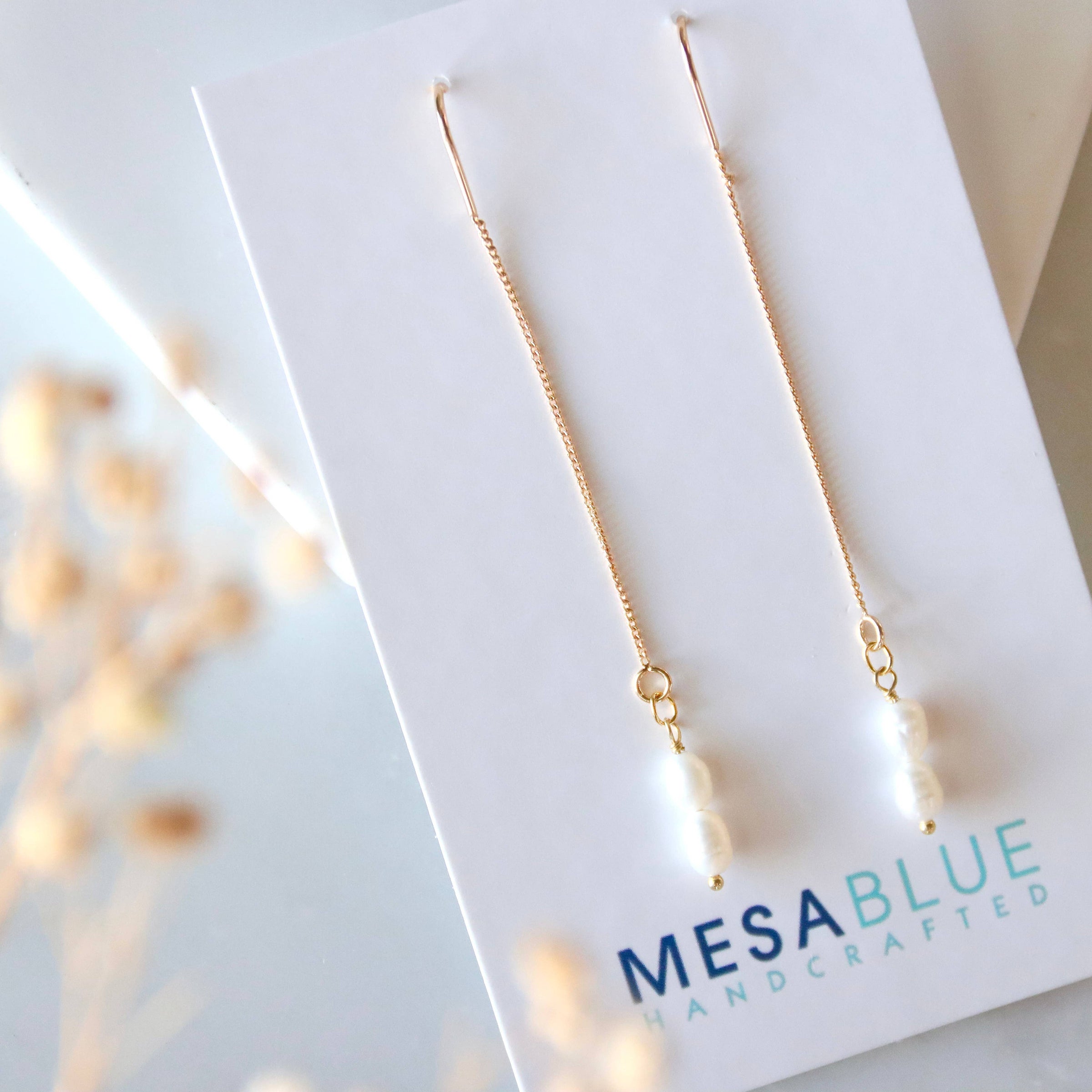 Gold necklace on a Mesa Blue branded card with a blurred background