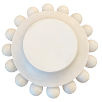 A round, off-white decorative object with a smooth central disc and a textured outer ring surrounded by small raised spheres, shown on a plain white background.