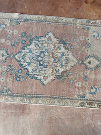 One-of-a-kind vintage Persian runner rug measuring approximately 2'11" x 12'5" with a faded dusty rose ground, blue and turquoise medallion motifs, ivory border and timeworn details.