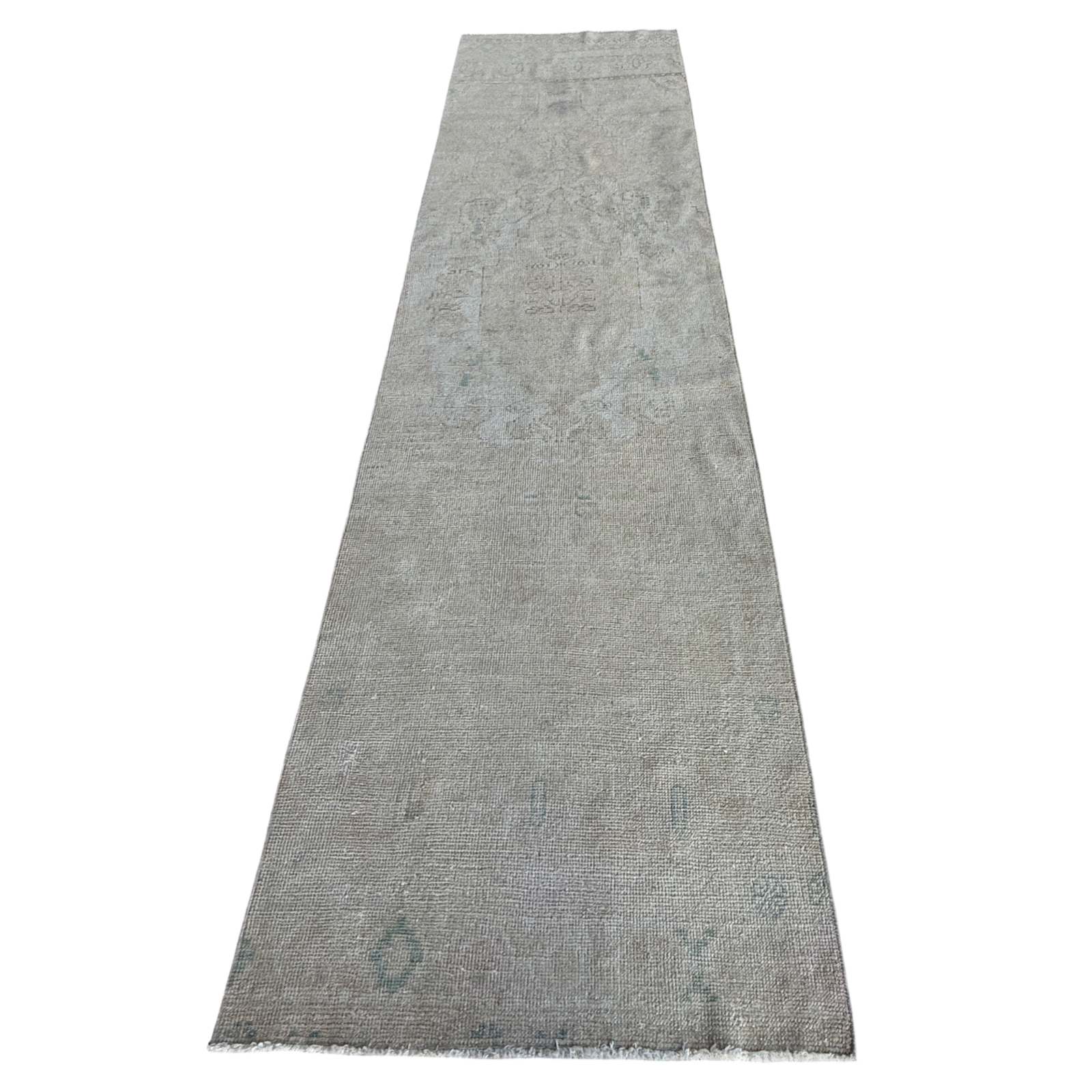 A long rectangular area rug in a distressed light gray color with subtle faded blue-gray and beige undertones, featuring a distressed traditional pattern and short fringe on the ends.