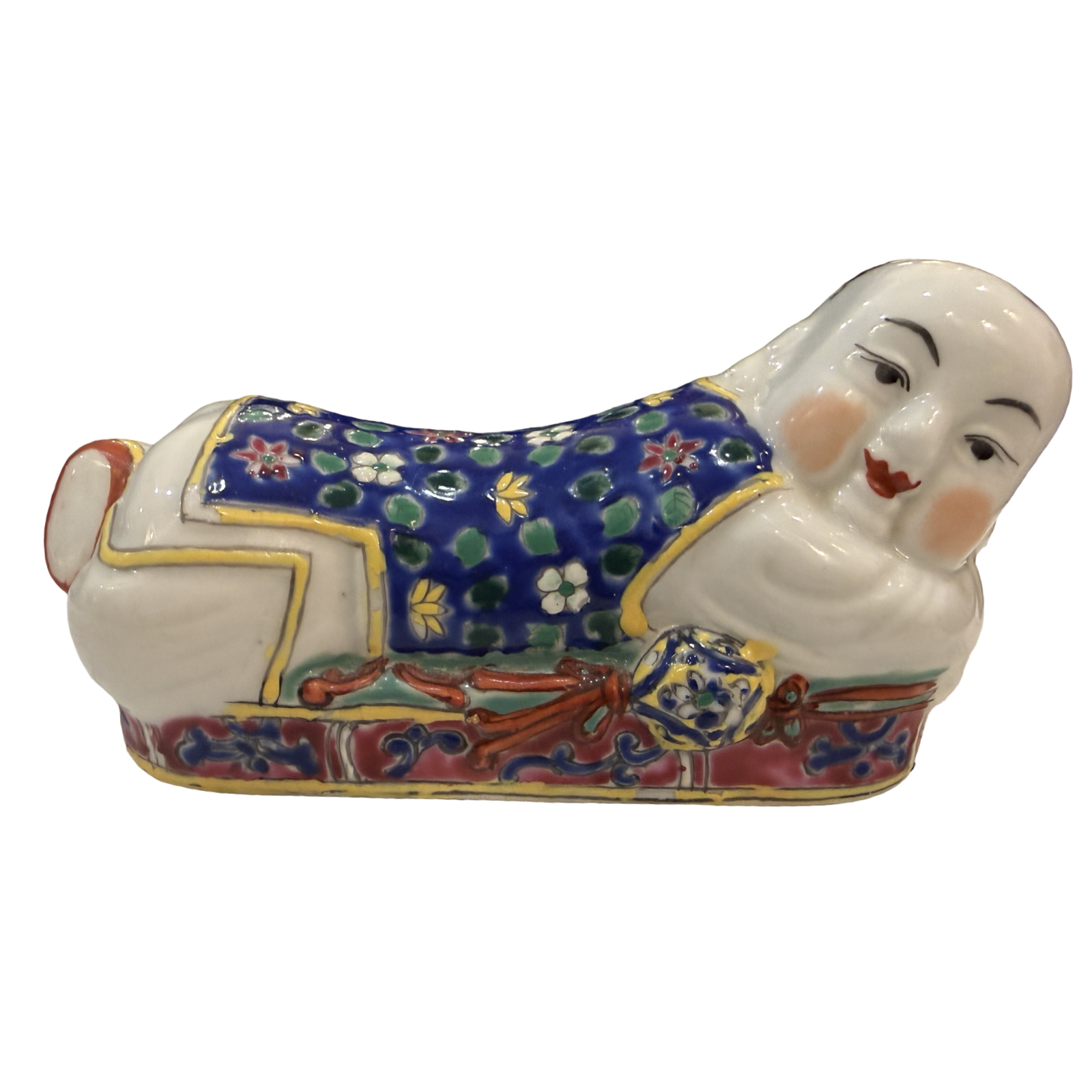 A ceramic figurine of a reclining figure in traditional East Asian-style clothing, decorated with a blue floral pattern, red and gold details, and a white face and hands, isolated on a white background.
