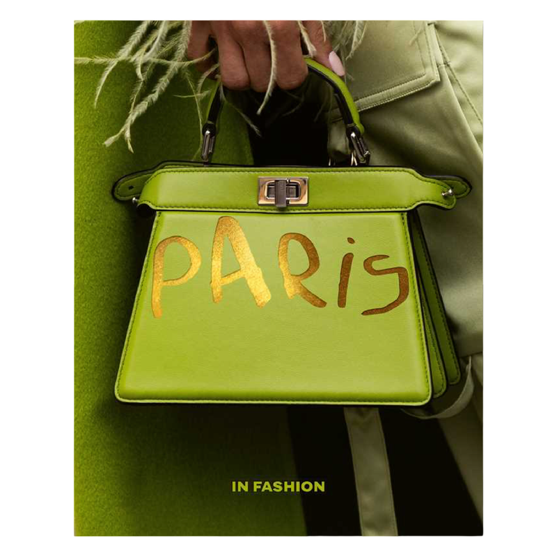 Green handbag with 'Paris' written on it, held by a person wearing a green coat.