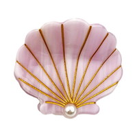 A pink clam shell-shaped brooch with gold metallic rays and a central white pearl, shown on a plain white background.