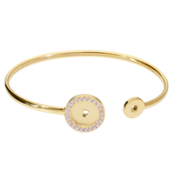 Gold bracelet with a circular charm on a white background