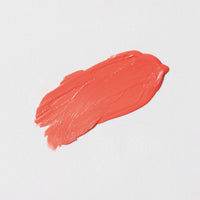 Smeared coral-colored lipstick on a light gray background