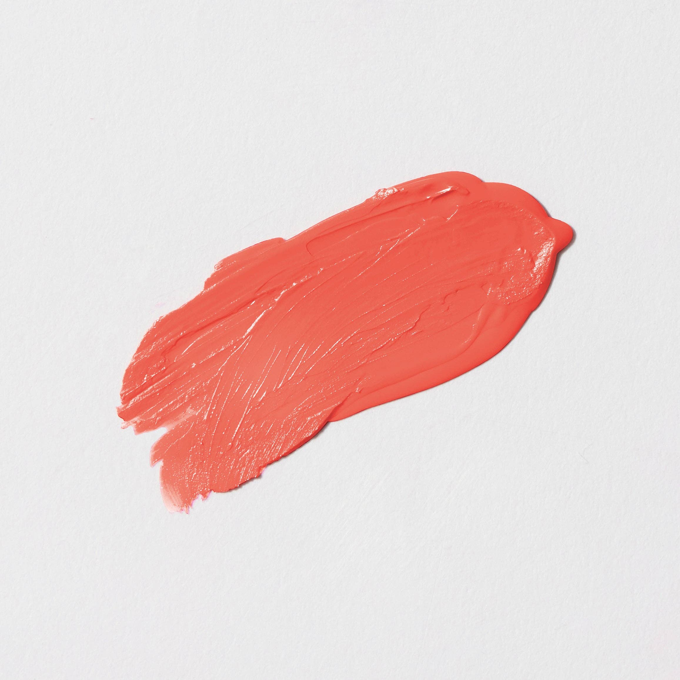 Smeared coral-colored lipstick on a light gray background