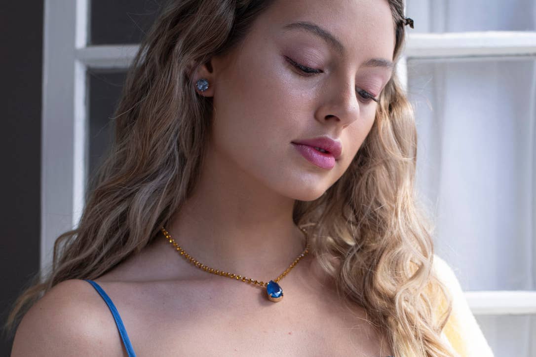 Woman wearing a necklace with a blue pendant indoors