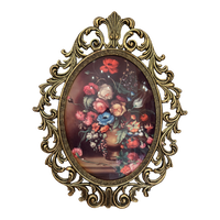 An ornate oval wall art piece featuring a classical-style floral bouquet painting in a gold-toned baroque frame, set against a plain white background.