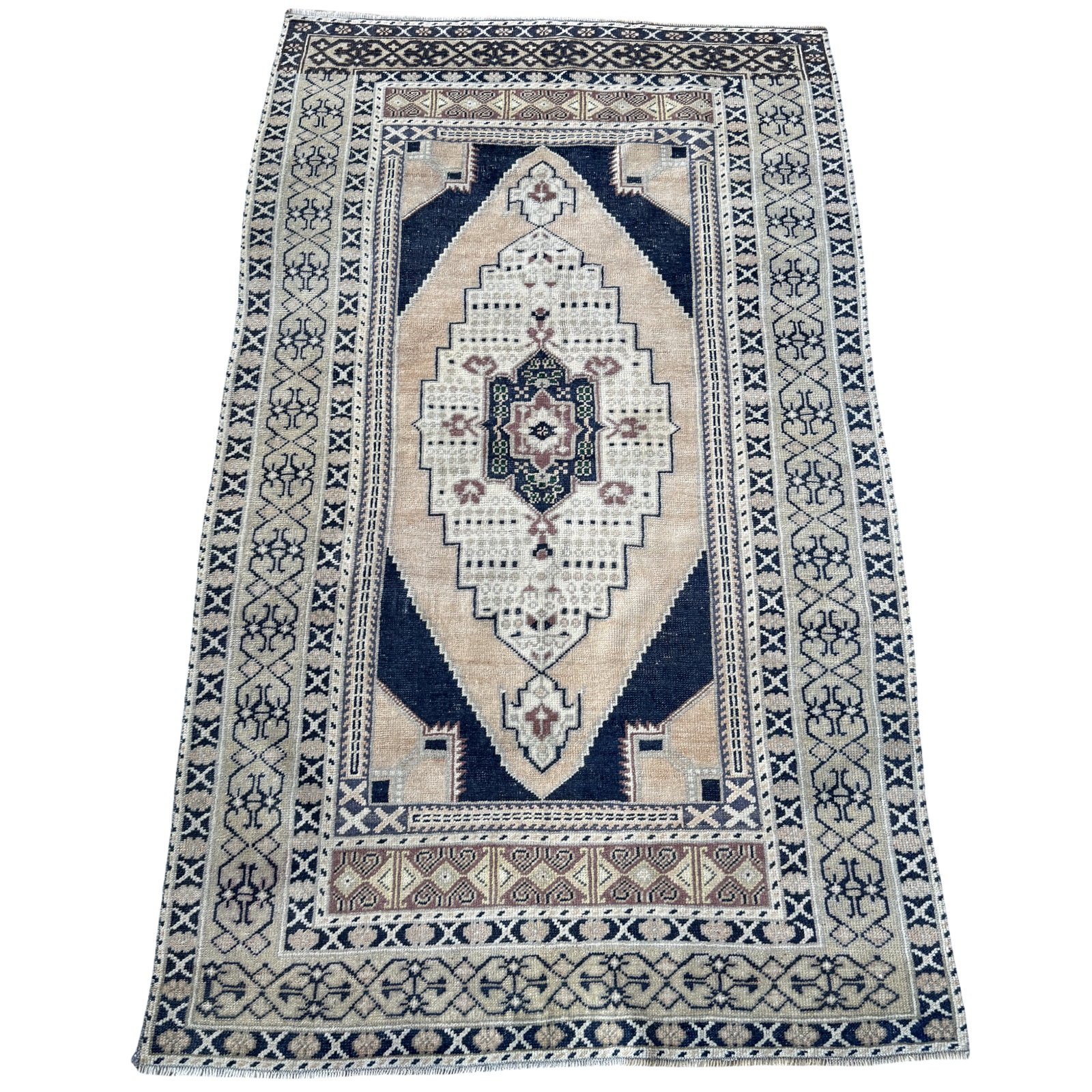 Vintage Turkish hand-knotted rug measuring approximately 3 feet 8 inches by 6 feet 4 inches with deep navy blue, cream, faded blush and green geometric medallion pattern.