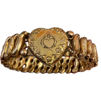 A vintage gold heart-shaped bracelet with a central engraved heart medallion and textured, wavy side bands, shown on a plain white background.
