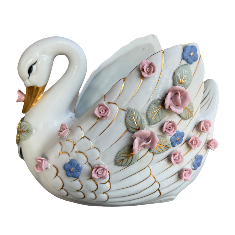 A decorative ceramic swan figurine with a glossy white body, gold-painted lines, and raised pink, blue, and green floral details, shown on a plain white background.