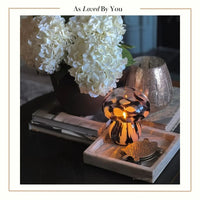 Decorative scene with a mushroom-shaped lamp, flowers, and books on a table.