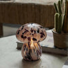 Mushroom-shaped lamp with marbled design on a table next to a cactus plant.