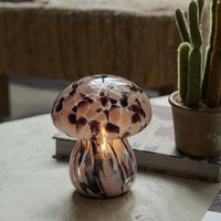 Mushroom-shaped lamp with marbled design on a table next to a cactus plant.