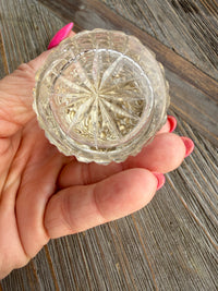 Hand holding a clear glass decorative object with intricate patterns on a wooden surface