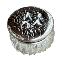 Decorative glass container with silver lid featuring angel design on a white background