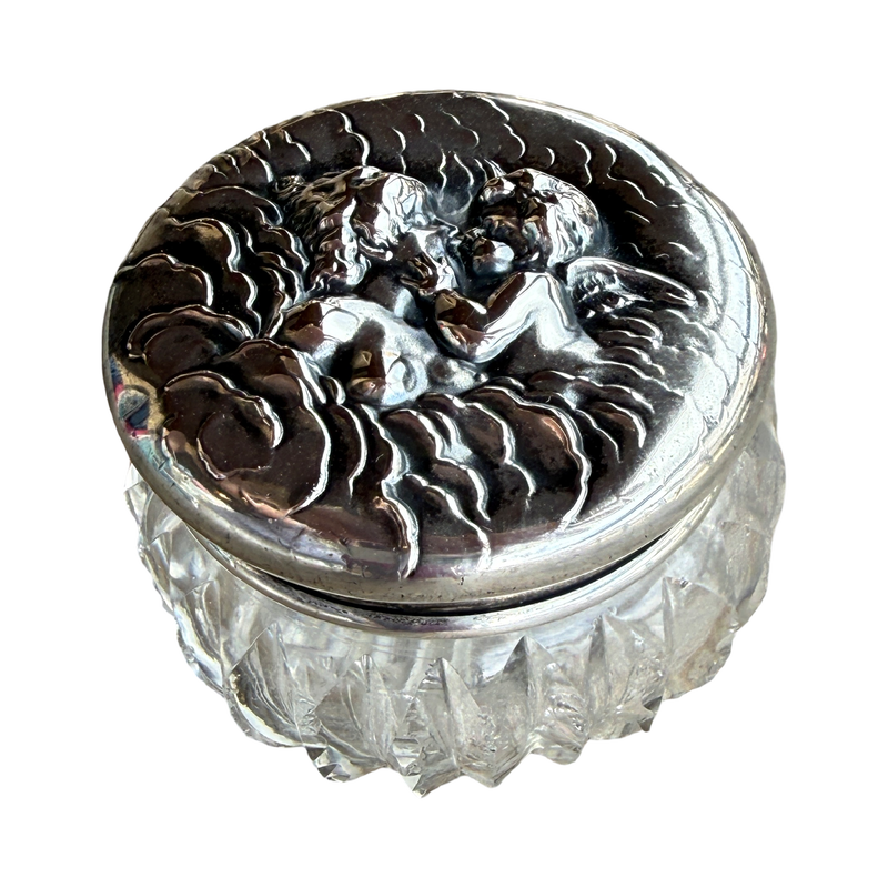 Decorative glass container with silver lid featuring angel design on a white background