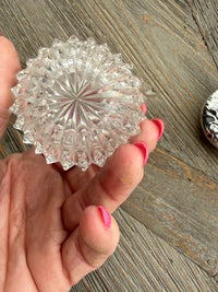 Clear glass knob held by a hand on a wooden surface