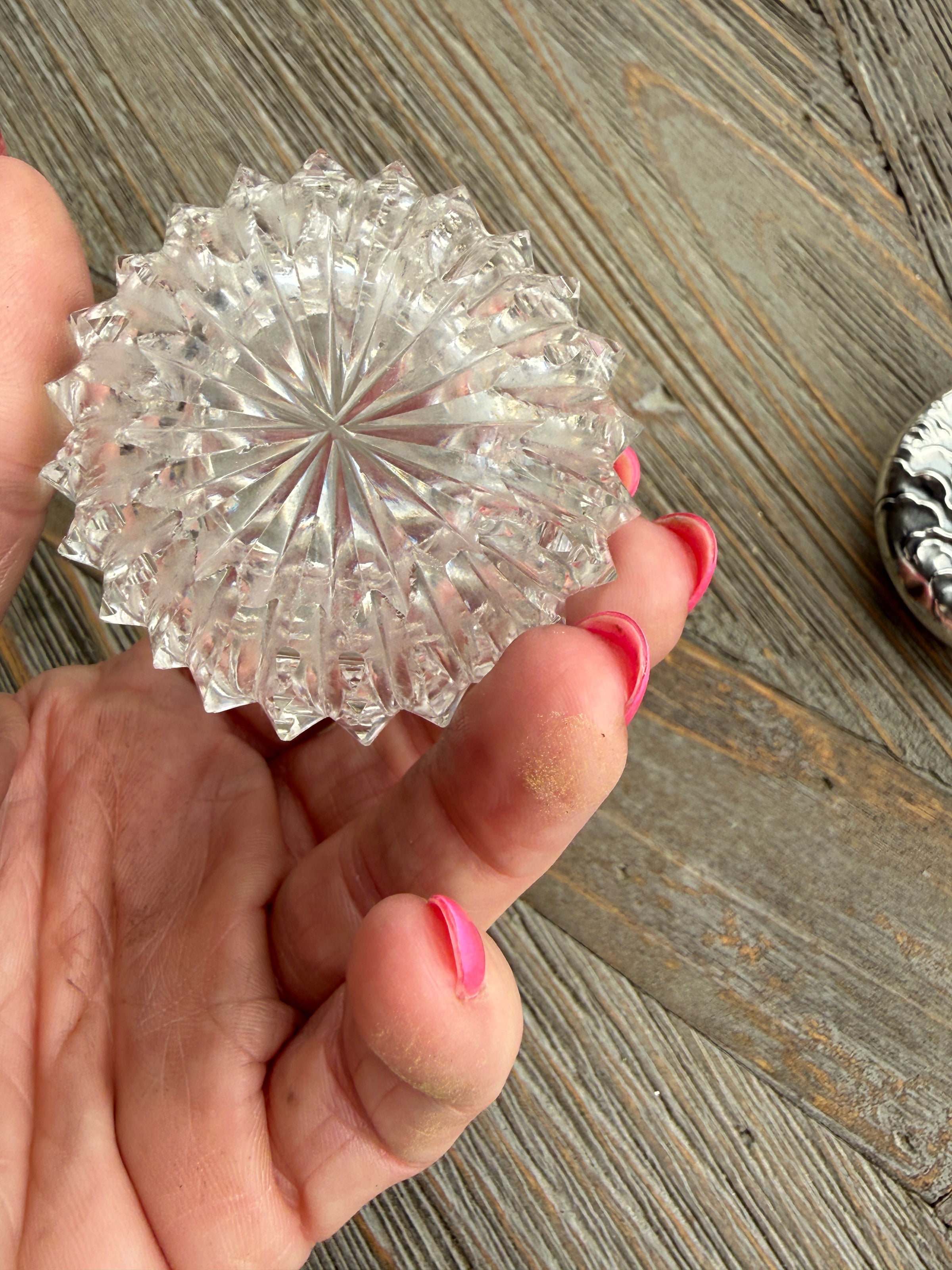 Clear glass knob held by a hand on a wooden surface