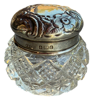 Decorative glass jar with silver lid on a white background