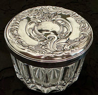 Decorative glass jar with silver lid on a dark background